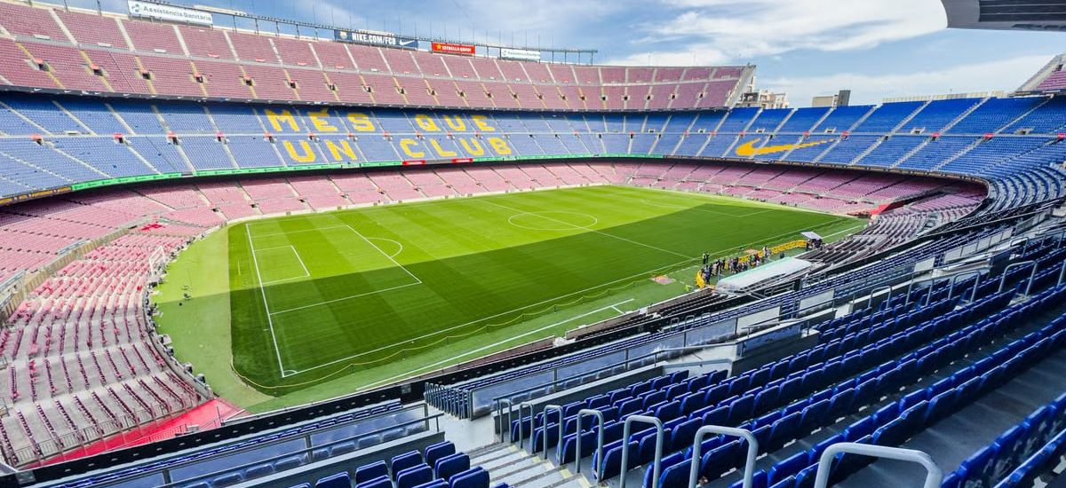 Wide-angle view of the iconic Camp Nou stadium in Barcelona, Spain, featuring its vibrant seating and green field.