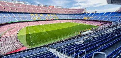 Wide-angle view of the iconic Camp Nou stadium in Barcelona, Spain, featuring its vibrant seating and green field.