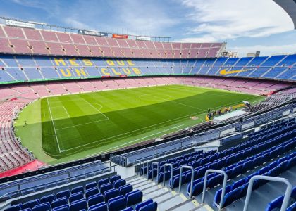 Wide-angle view of the iconic Camp Nou stadium in Barcelona, Spain, featuring its vibrant seating and green field.