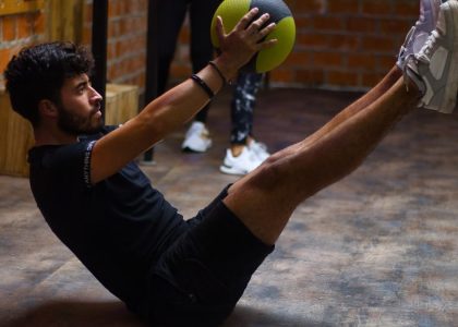 Focused man performing core exercises with a medicine ball in an indoor gym highlighting fitness and strength.